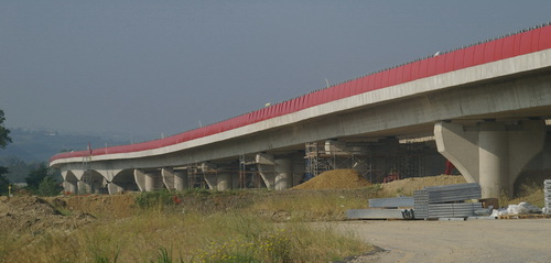 Veduta del nuovo viadotto autostradale sul Tanaro caratterizzato dai pannelli di colore rosso acceso disposti per centinaia di metri lungo la struttura viaria.