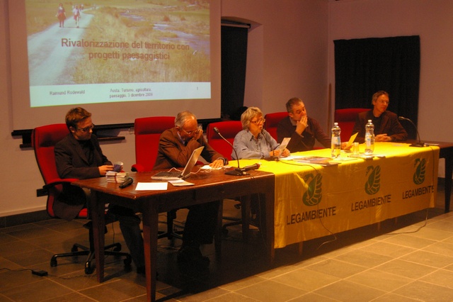 Tavolo dei relatori del Convegno "Una altra strada per la montagna? Paesaggio, Agricoltura, Economia" tenutosi a Saint-Christophe. Nella foto da (sx) verso (dx): Dott. For. Stefano Lunardi (Coordinatore del Progetto "Ayas Km 0"), Prof. Andrea Cavallero (Dipartimento di Agronomia, Selvicoltura e Gestione del Territorio della Facoltà di Agraria dell Università di Torino), Dott.ssa Maria Pia Simonetti (Presidente del Circolo valdostano Legambiente), Dott. Andrea Barmaz (Direttore della Ricerca dell Istitut agricole Régional) e Dott. Raimund Rodewald (Direttore  della Fondazione Svizzera per la Tutela del paesaggio).